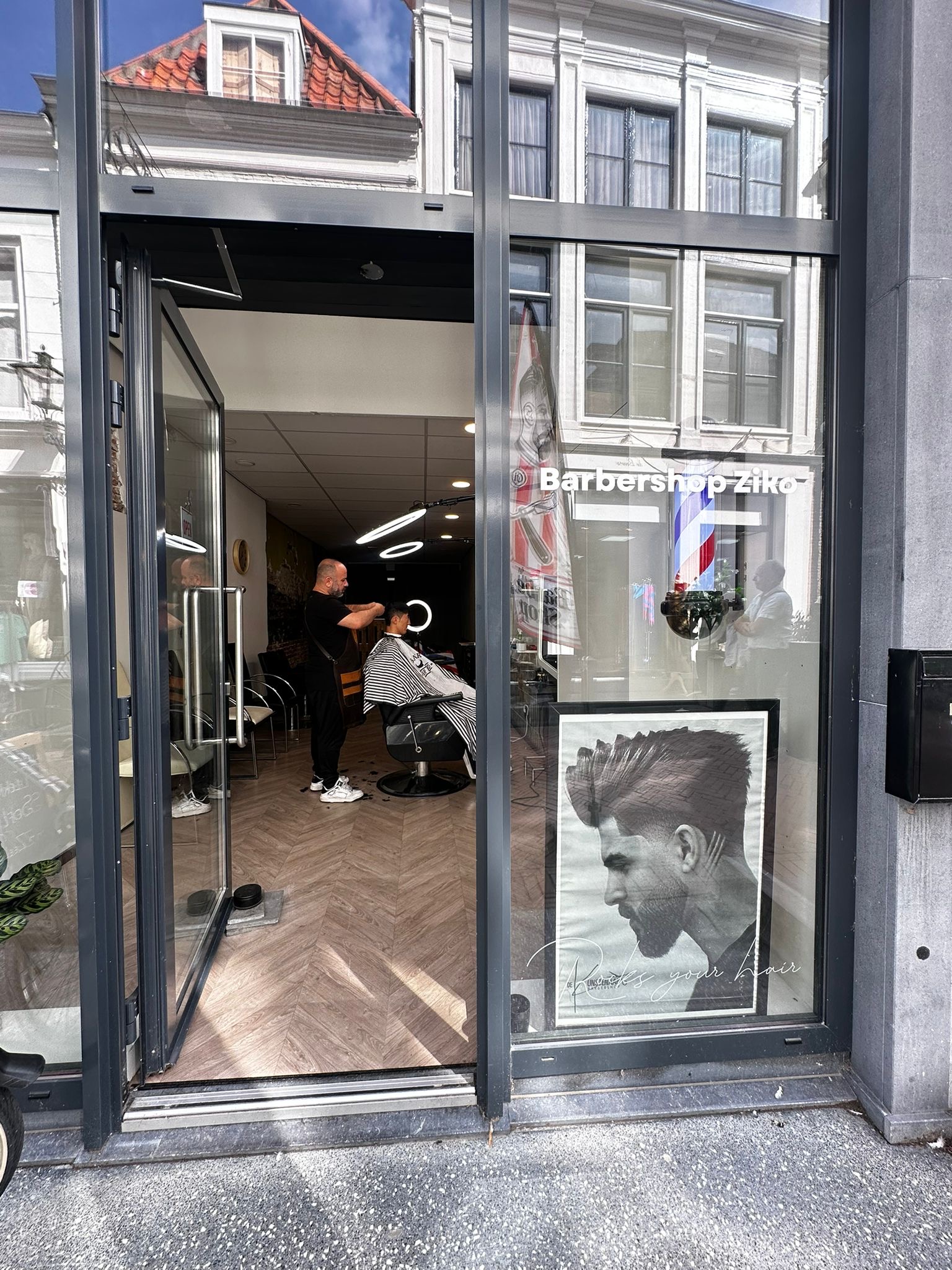 De open winkeldeur met de naam Barbershop Ziko op het raam